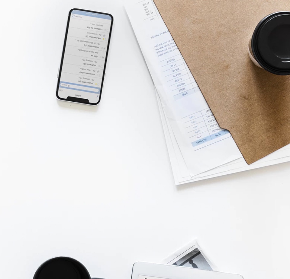 Birds eye view of a desktop with an iphone and file folder.